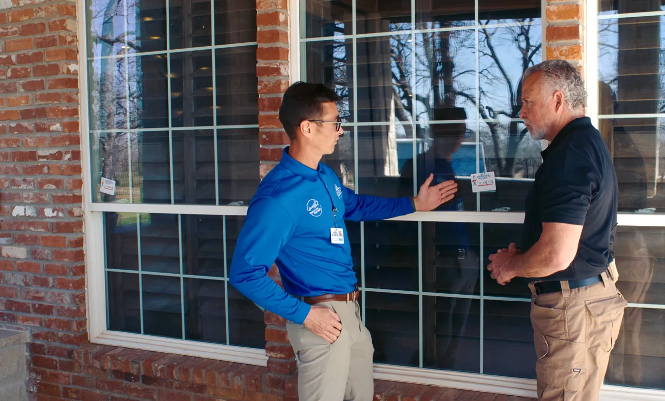 Homeowner reviewing a replacement window estimate with a consultant at the kitchen table